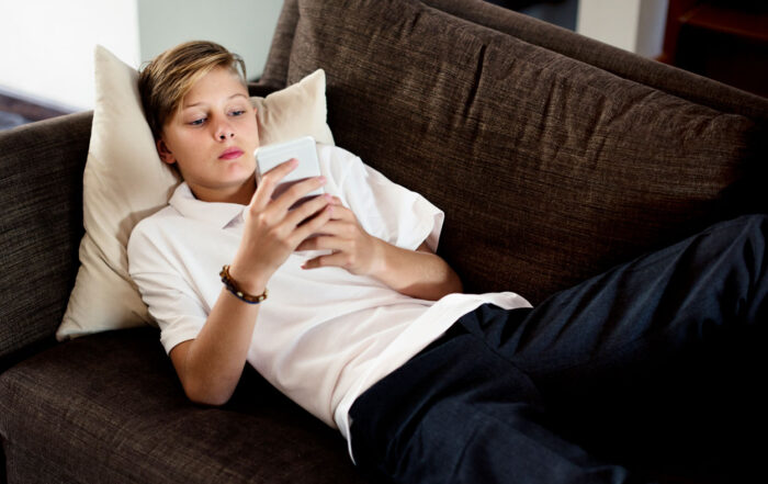 teenage boy on phone on couch